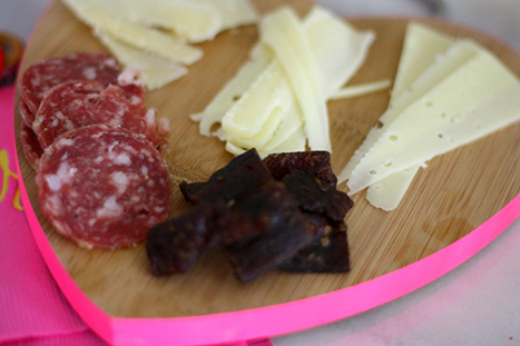 a heart shaped cutting board with meat and cheese